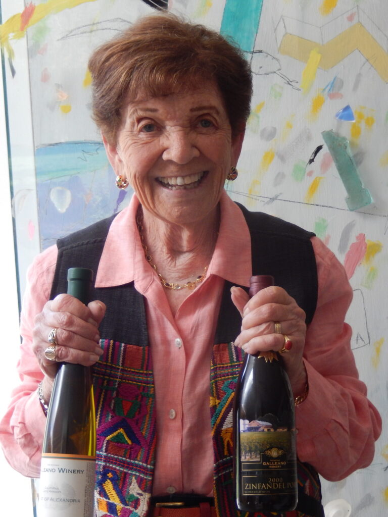 smiling woman in a pink shirt holding a bottle of wine